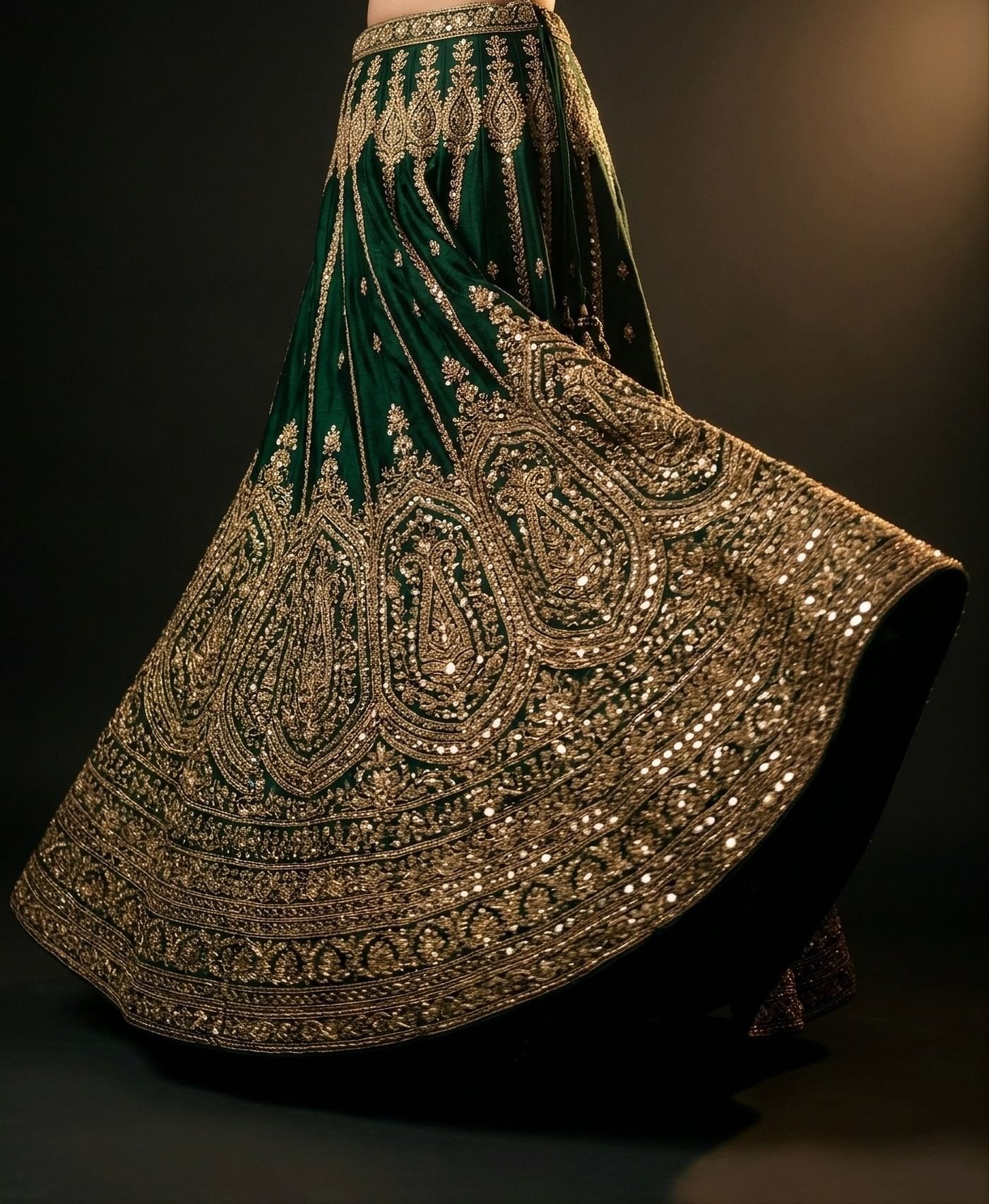 Heavily embroidered emerald lehenga skirt with gold zari and mirror work, caught mid-turn